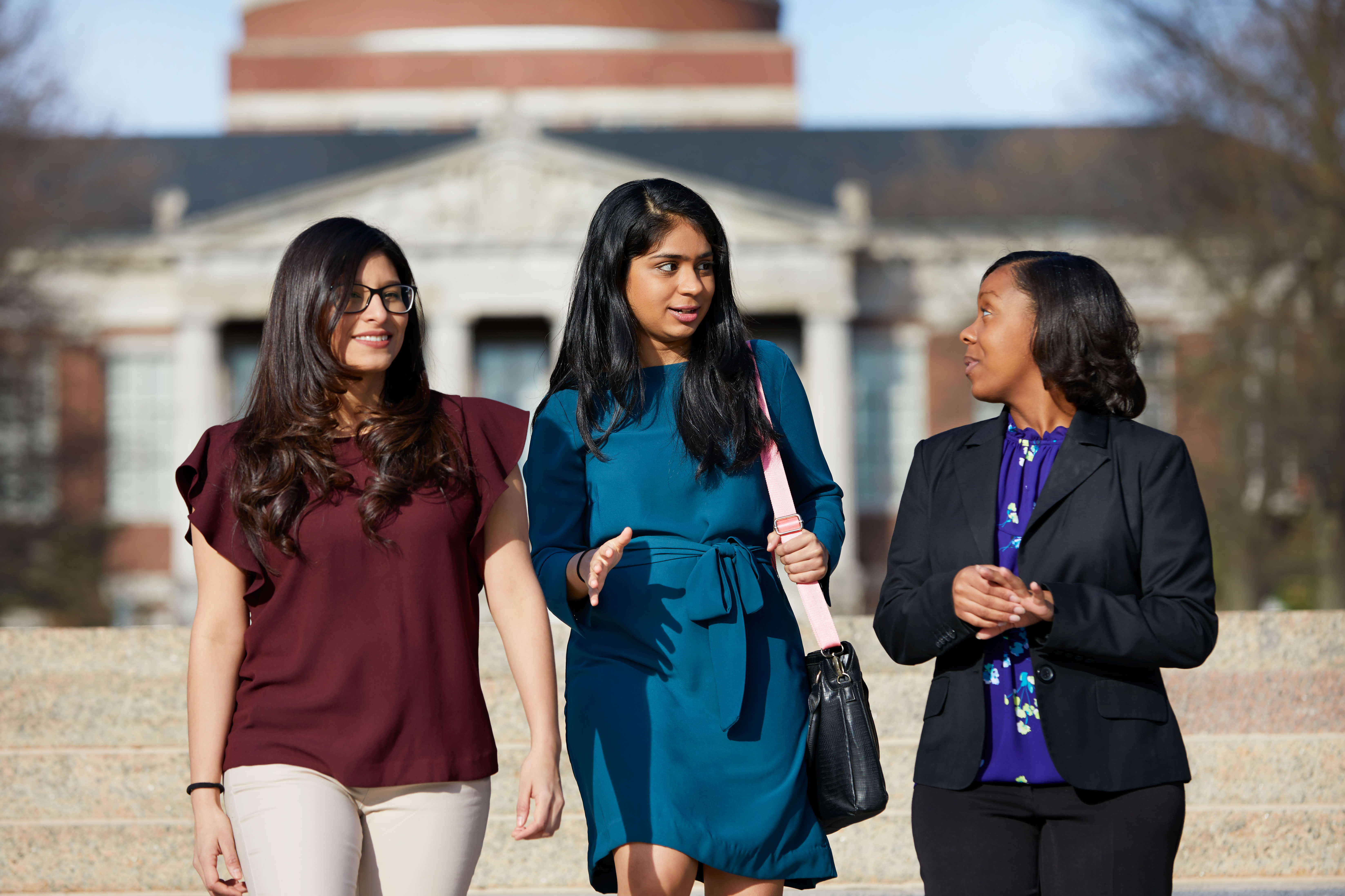 Three female Simon Business School students walk along the University of Rochester campus