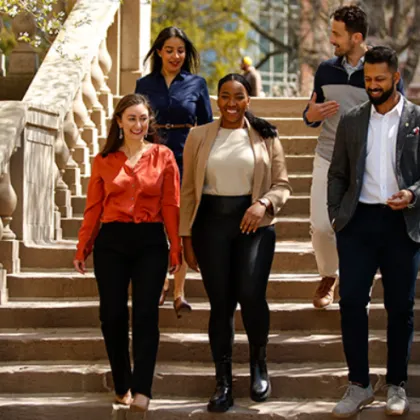 Students smile, laugh, and talk as they walk down a set of stars on a spring day on campus